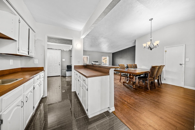 kitchen with dark hardwood / wood-style floors, white cabinets, and vaulted ceiling