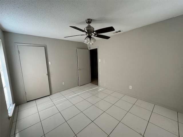 unfurnished bedroom with a closet, a textured ceiling, light tile patterned floors, and ceiling fan