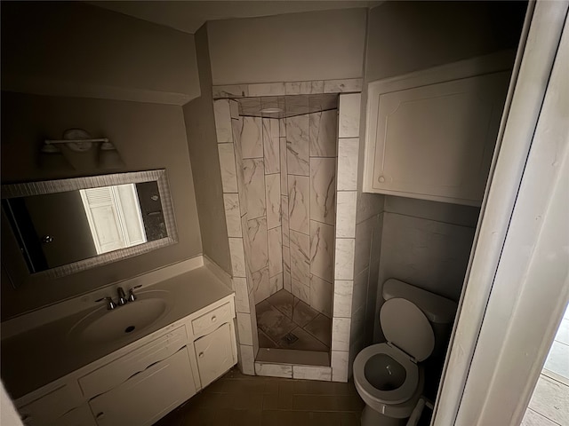 bathroom featuring vanity, a tile shower, toilet, and tile patterned flooring