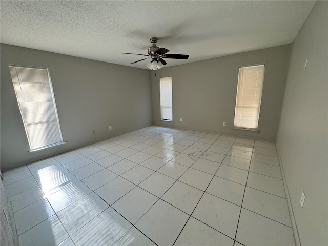 tiled empty room with a wealth of natural light, a textured ceiling, and ceiling fan