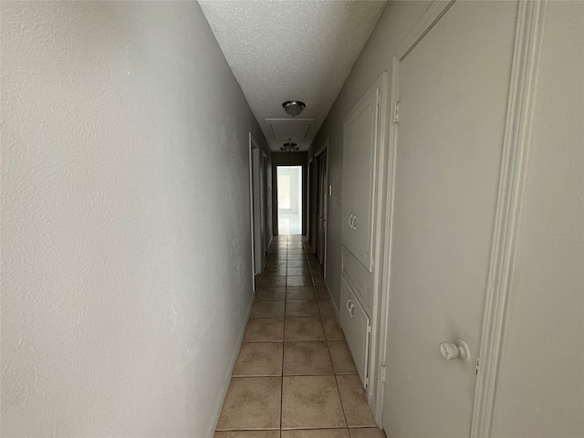 hall with a textured ceiling and light tile patterned floors