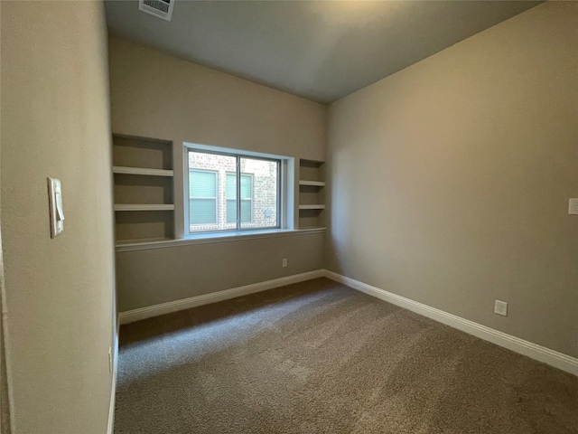 carpeted spare room featuring built in features