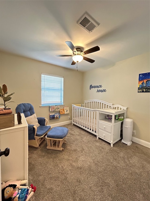 carpeted bedroom with ceiling fan and a crib