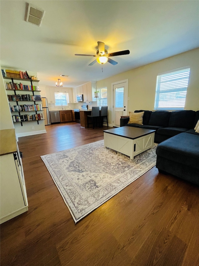 living room featuring ceiling fan with notable chandelier and dark hardwood / wood-style flooring