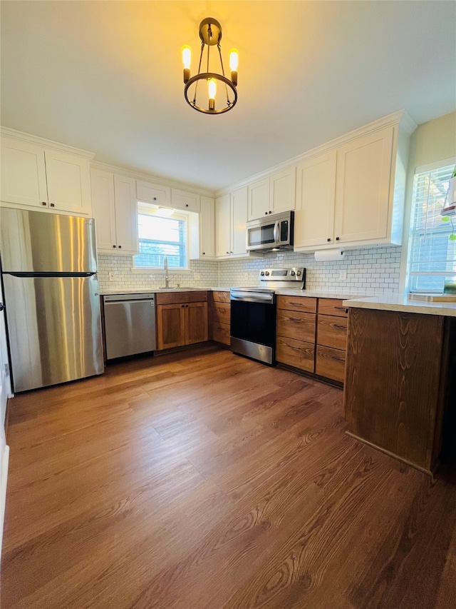 kitchen featuring decorative backsplash, dark hardwood / wood-style floors, white cabinets, pendant lighting, and appliances with stainless steel finishes