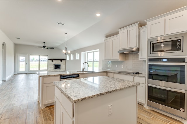 kitchen with sink, vaulted ceiling, kitchen peninsula, and a healthy amount of sunlight