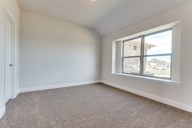 carpeted spare room featuring vaulted ceiling