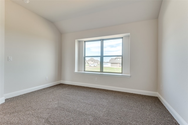 spare room featuring carpet and vaulted ceiling