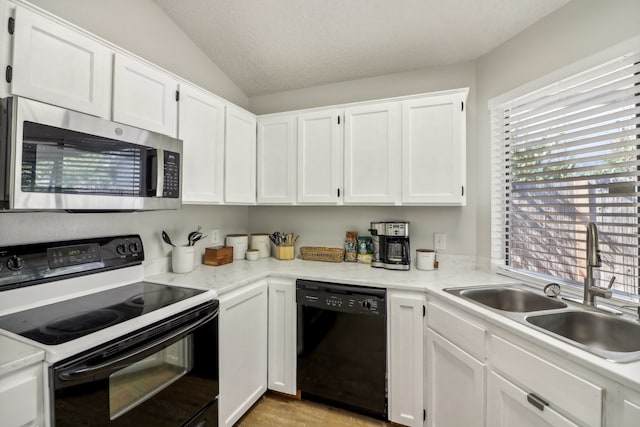 kitchen featuring sink, black appliances, white cabinetry, and vaulted ceiling