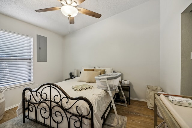 bedroom with electric panel, dark hardwood / wood-style floors, a textured ceiling, and ceiling fan