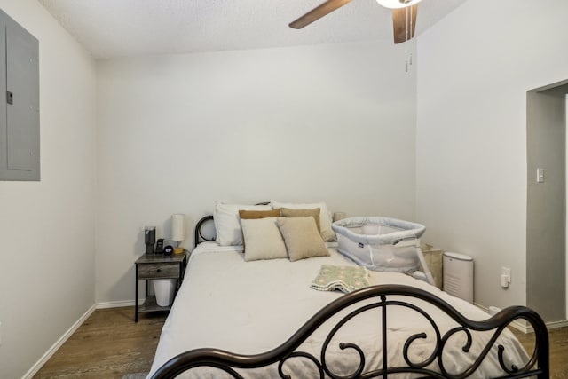 bedroom with electric panel, ceiling fan, a textured ceiling, and dark hardwood / wood-style flooring