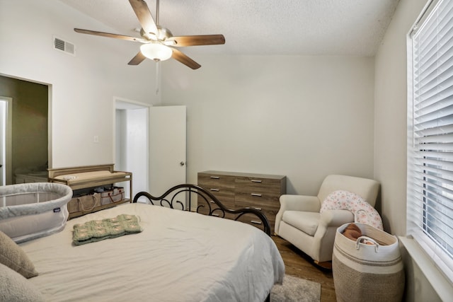 bedroom with multiple windows, ceiling fan, wood-type flooring, and vaulted ceiling