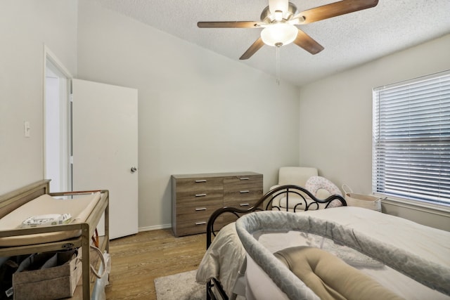 bedroom featuring light hardwood / wood-style flooring, a textured ceiling, and ceiling fan