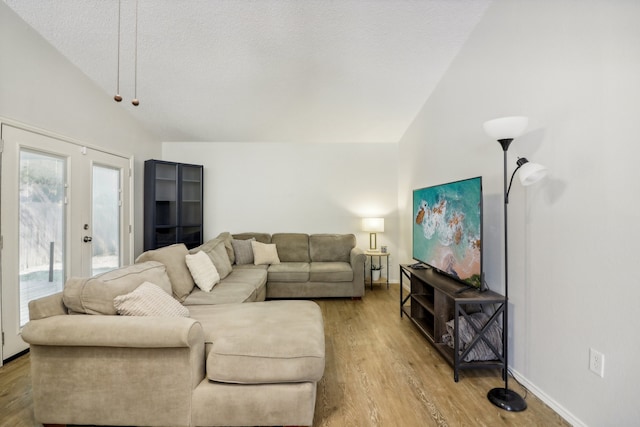 living room featuring high vaulted ceiling, french doors, a textured ceiling, and light hardwood / wood-style floors