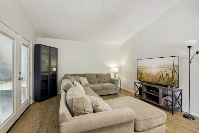 living room with a textured ceiling, wood-type flooring, and vaulted ceiling