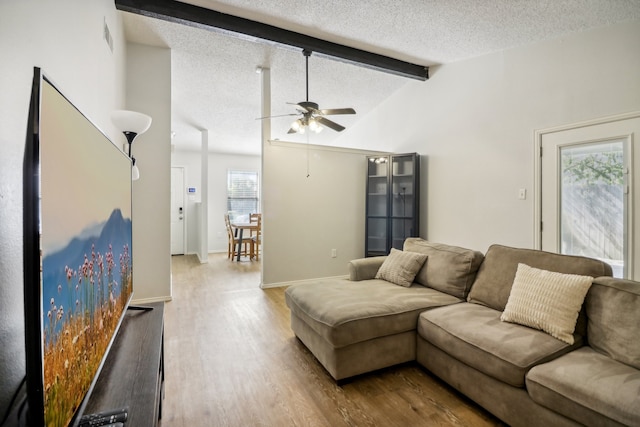 living room featuring vaulted ceiling with beams, hardwood / wood-style floors, a textured ceiling, and ceiling fan