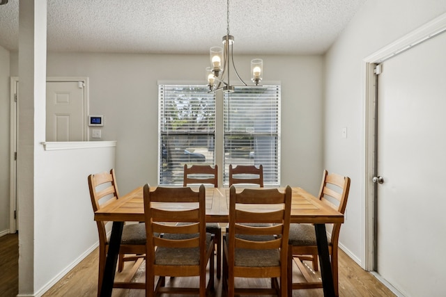 dining room with hardwood / wood-style floors, a notable chandelier, and a textured ceiling