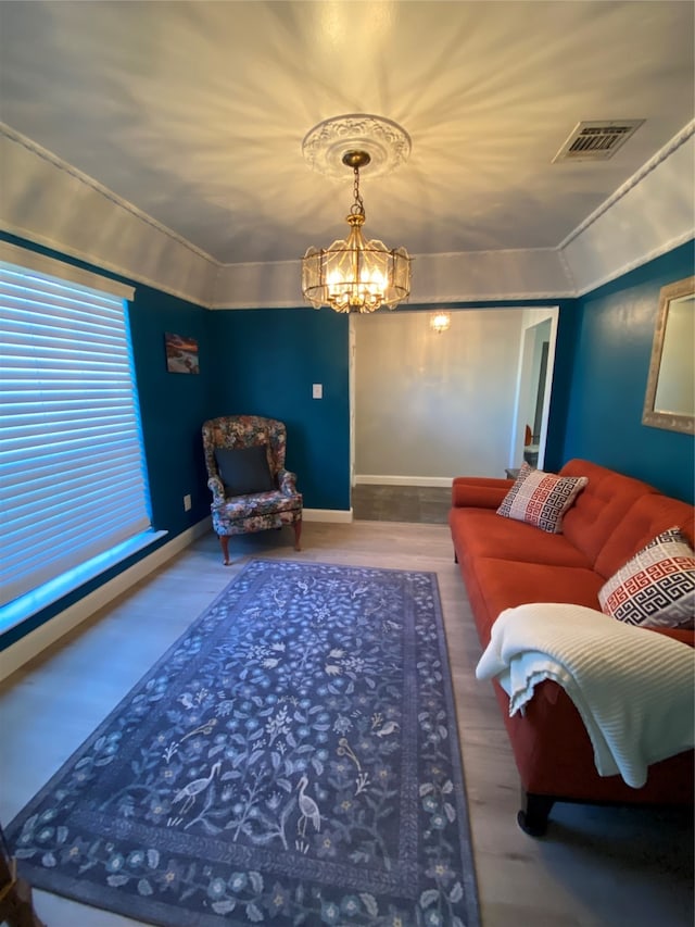 living room featuring crown molding, hardwood / wood-style flooring, and a notable chandelier