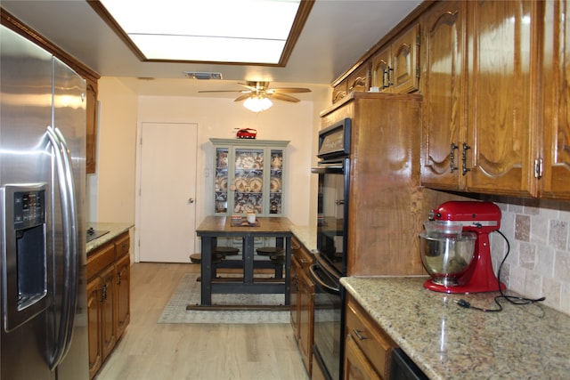 kitchen featuring tasteful backsplash, ceiling fan, black appliances, a skylight, and light hardwood / wood-style floors