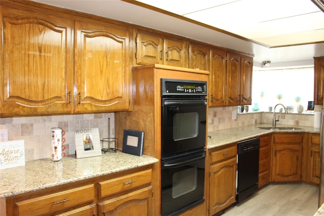 kitchen featuring decorative backsplash, sink, black appliances, light wood-type flooring, and light stone counters