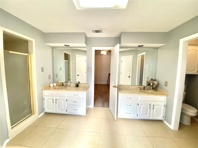 bathroom featuring vanity, toilet, a shower with shower door, and tile patterned floors