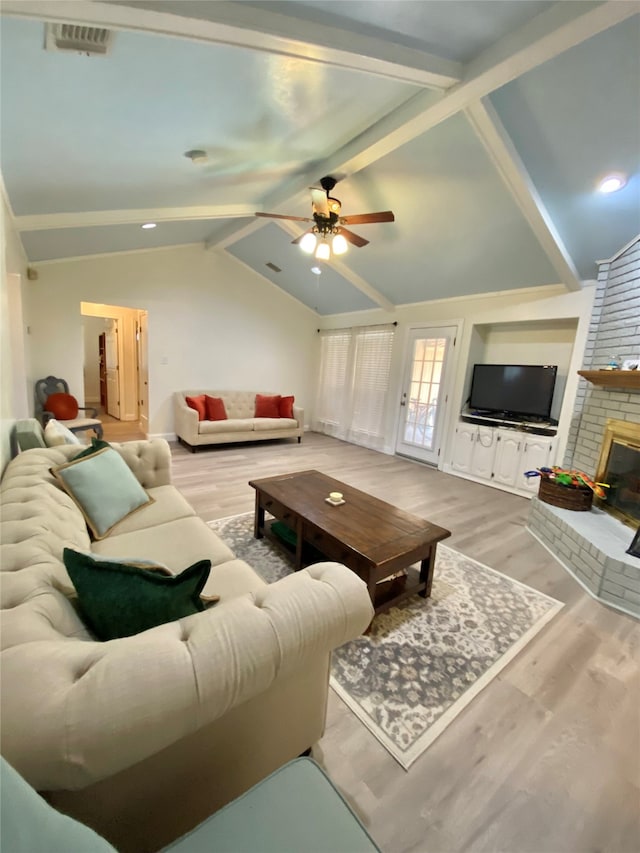 living room featuring lofted ceiling with beams, a fireplace, light hardwood / wood-style floors, and ceiling fan