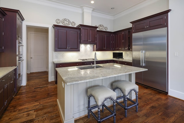 kitchen with dark hardwood / wood-style floors, stainless steel appliances, and a center island with sink