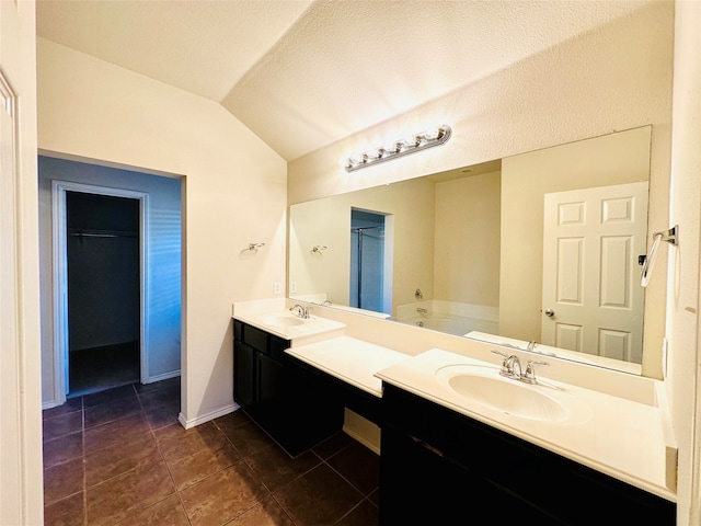 bathroom with lofted ceiling, tile patterned floors, a tub to relax in, vanity, and a textured ceiling