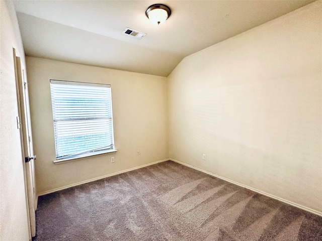 carpeted spare room featuring vaulted ceiling