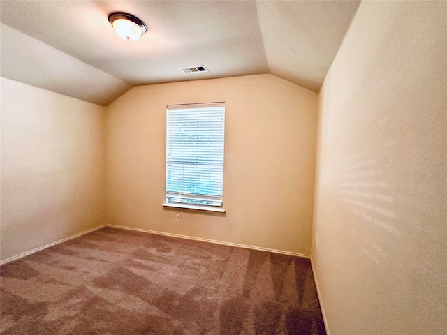 carpeted empty room with vaulted ceiling