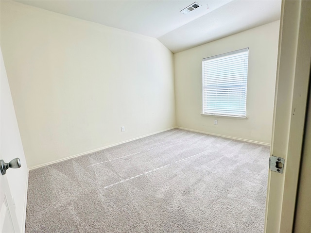 carpeted empty room featuring vaulted ceiling