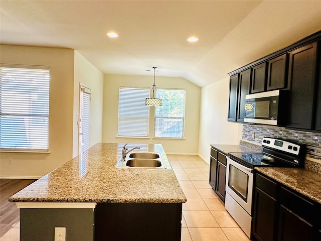 kitchen featuring lofted ceiling, a kitchen island with sink, hanging light fixtures, sink, and appliances with stainless steel finishes