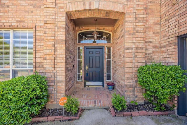 view of exterior entry featuring brick siding