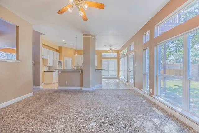 unfurnished living room with baseboards, light colored carpet, and ceiling fan