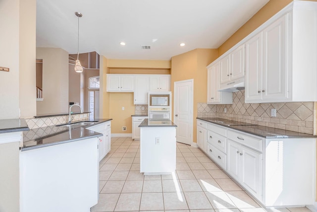 kitchen featuring pendant lighting, sink, white appliances, white cabinetry, and a center island