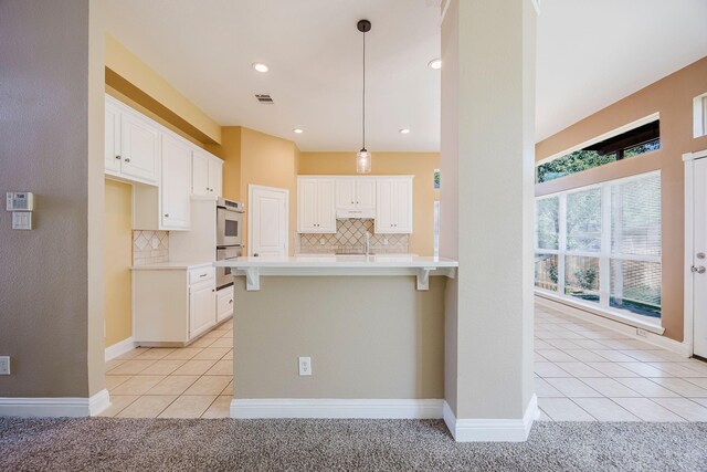 kitchen with double oven, decorative backsplash, light countertops, and light tile patterned floors