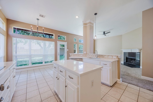 kitchen featuring hanging light fixtures, a sink, light tile patterned floors, visible vents, and a kitchen island