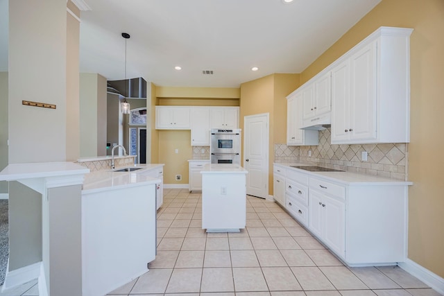 kitchen with double oven, backsplash, a sink, a center island, and black electric stovetop