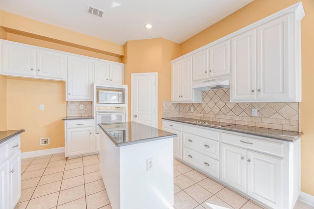 kitchen featuring white cabinetry, light tile patterned floors, white appliances, and a kitchen island