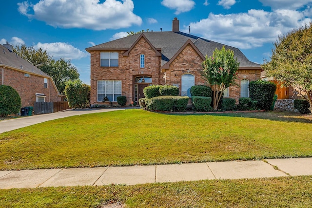 french country style house featuring a chimney, brick siding, fence, and a front yard