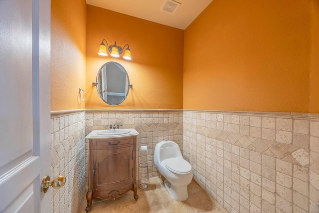 bathroom with tile patterned floors, vanity, toilet, and tile walls