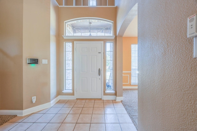 entrance foyer with a towering ceiling and light tile patterned floors