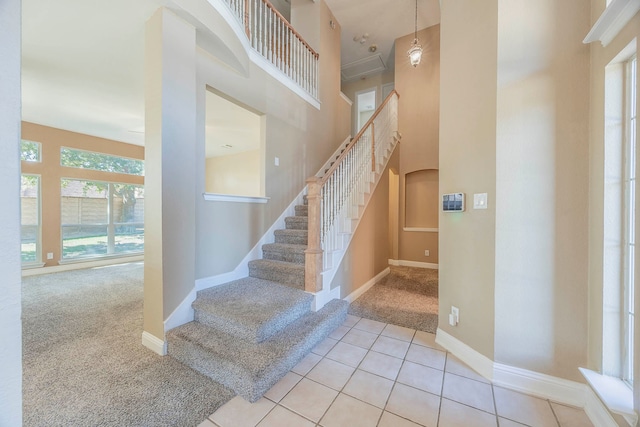 stairway featuring tile patterned flooring and a towering ceiling