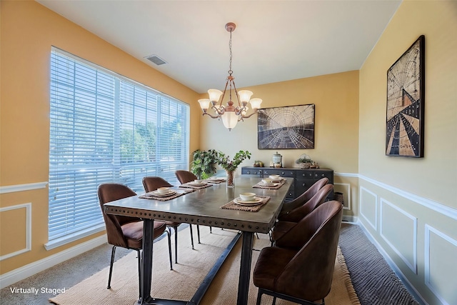 dining space with carpet and a notable chandelier