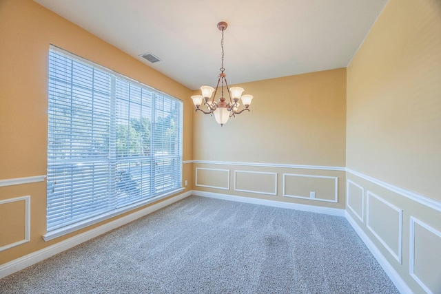 empty room with a chandelier and carpet flooring