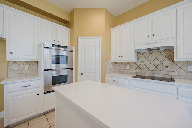 kitchen featuring tasteful backsplash, stainless steel double oven, black electric stovetop, white cabinetry, and under cabinet range hood