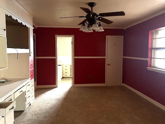 interior space with crown molding, light colored carpet, and ceiling fan