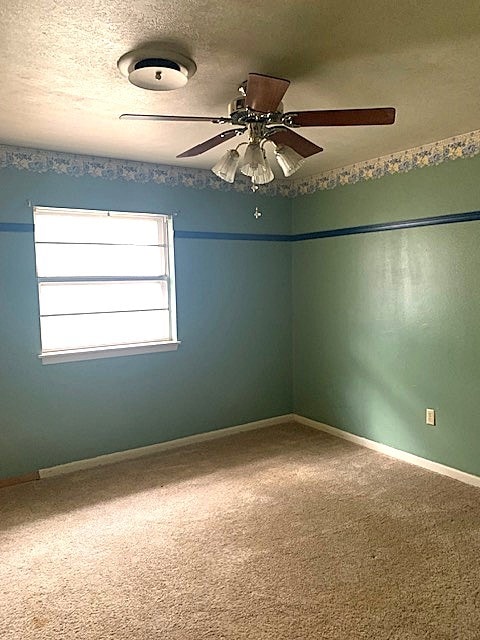 carpeted spare room with a textured ceiling and ceiling fan