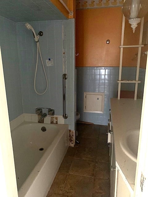 807 N Morris Ave, Rotan, TX 79546 - bathroom with vanity, tile walls, tile patterned flooring, and shower / washtub combination