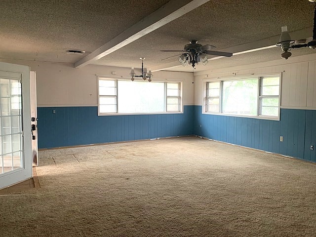 807 N Morris Ave, Rotan, TX 79546 - carpeted spare room with a textured ceiling, wainscoting, ceiling fan, wooden walls, and beamed ceiling